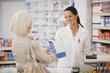image d'une patiente et d'une pharmacienne tenant une poche à médicaments à sa cliente