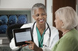 photo d'une médecin souriante montrant un dossier sur tablette à sa patiente