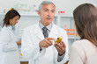 image d'un pharmacien conseillant une patiente sur le medicament qui tient dans la main