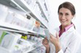 photo représentant une pharmacienne souriante lisant l'ordonnance et cherchant les médicaments