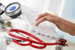 image représentant la main d'un medecin tapant sur un clavier d'ordinateur et stetoscope rouge
